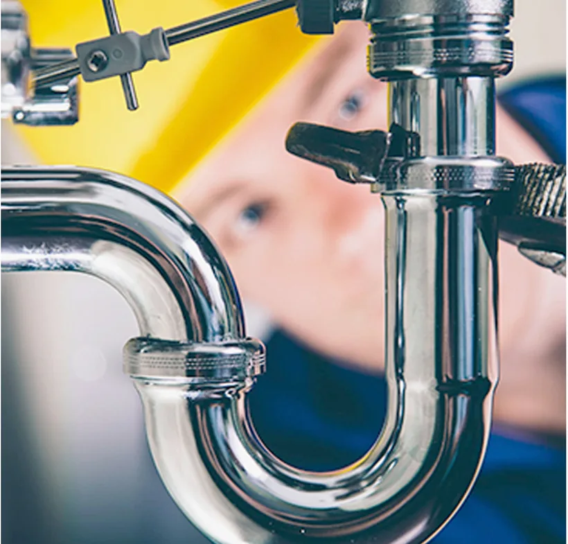 Plumber tightening a chrome P-trap beneath a sink
